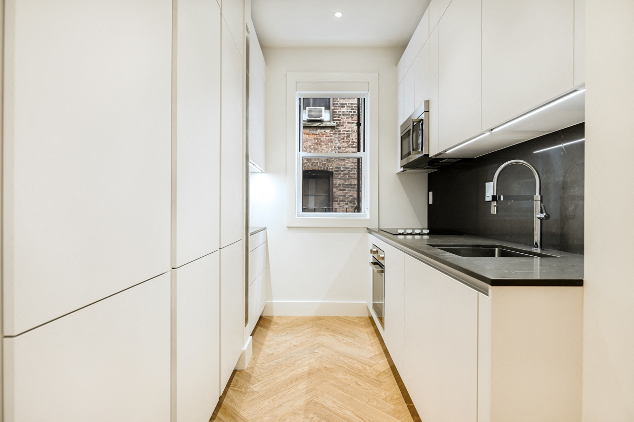 A kitchen with white cabinets and a black counter top.